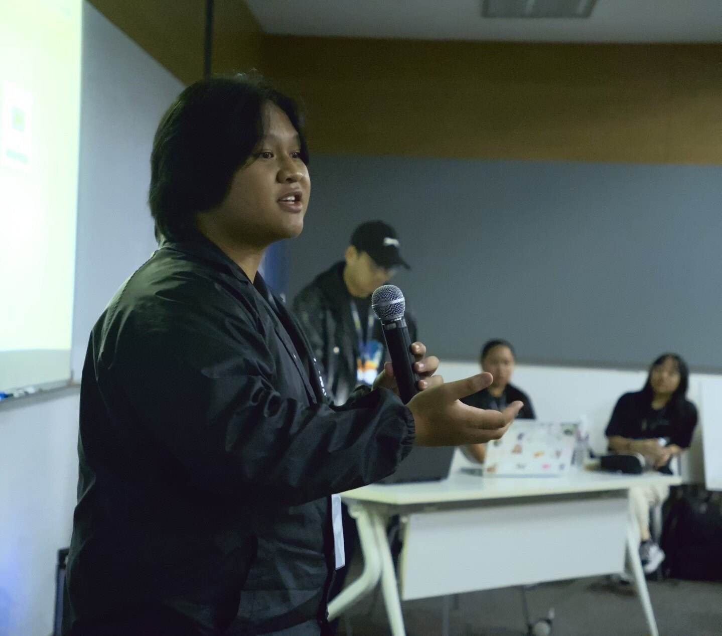 A TheRookies member pitching on stage with a microphone during HackWknd 2025