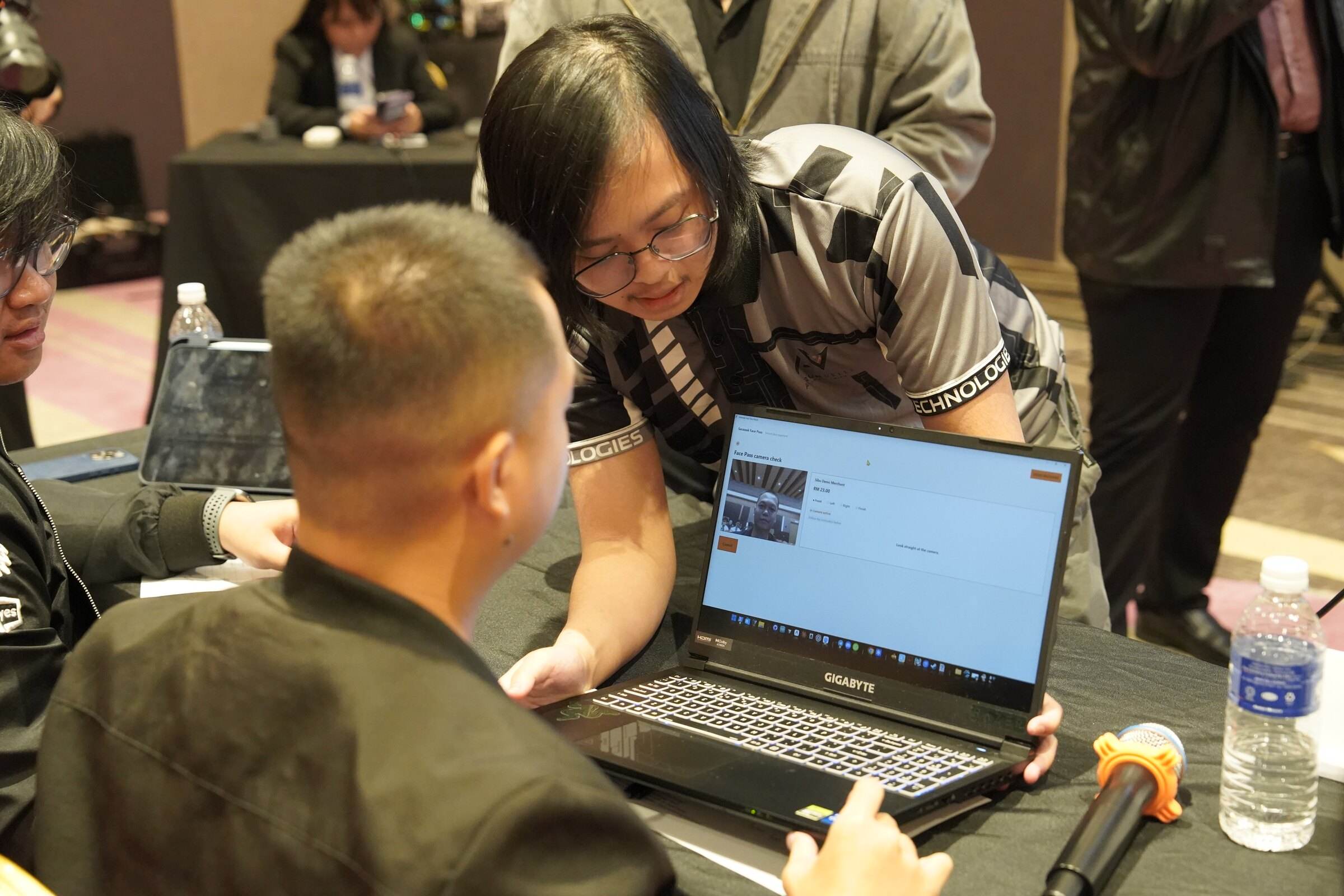 A team member in an Aurumvelle jersey showing the product on a laptop to a judge