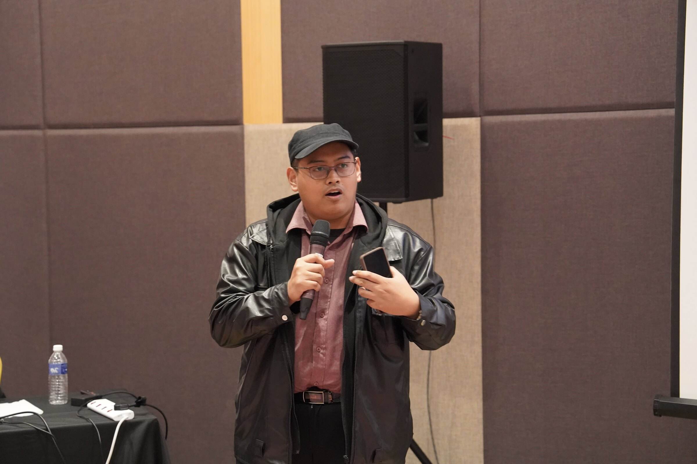 A team member pitching to the judging panel with a microphone at Sibu HackWknd 2026
